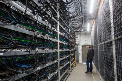 A photograph showcasing a large-scale Bitcoin mining farm with rows of mining rigs and optimized network infrastructure.